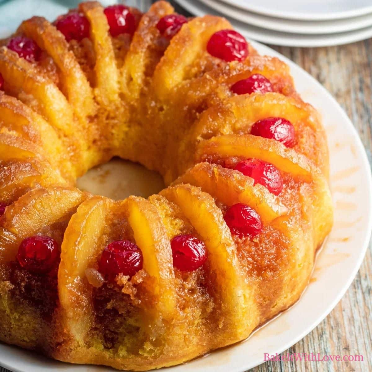 Best pineapple upside down cake recipe with the baked cake setting on a white plate on a wooden surface.