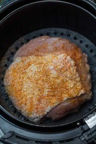Process photo 1 seasoned turkey breast in air fryer basket.