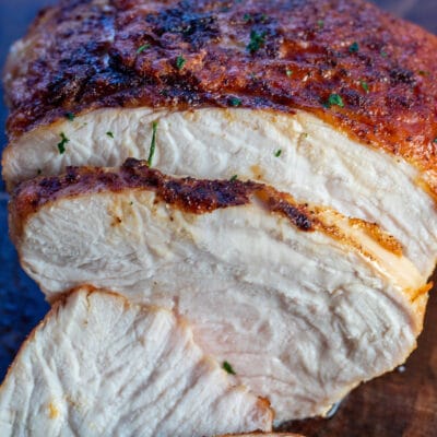 Closeup on the air fryer turkey breast sliced and served on wooden cutting board.