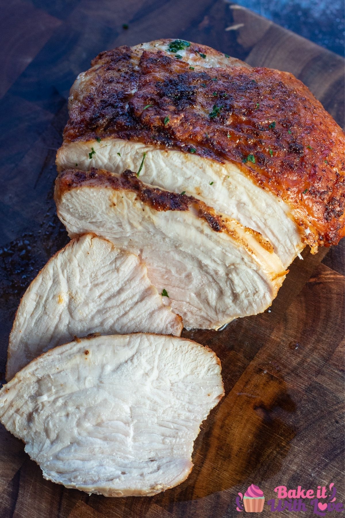 Tall image of the air fryer turkey breast on wooden cutting board.