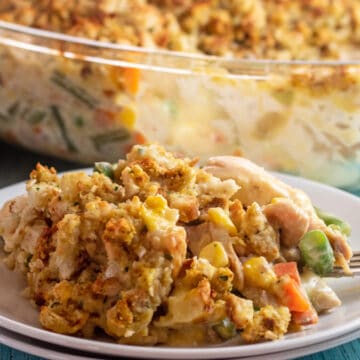 Wide image of the plated chicken stuffing casserole with glass baking dish in background.