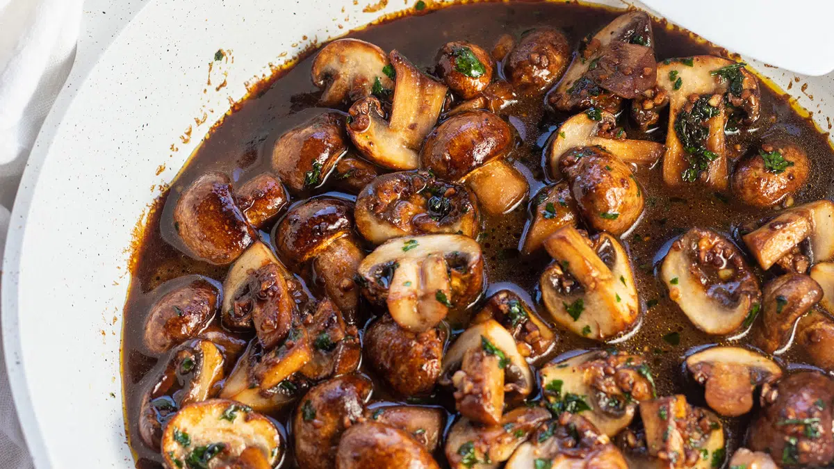 Garlic butter mushrooms in sauce wiht parsley garnish.