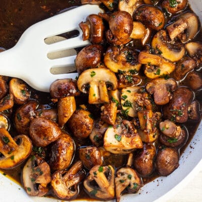 Garlic butter mushrooms in skillet with white spatula.