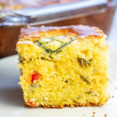 Jiffy jalapeno cornbread served on white plate with baking dish in background.