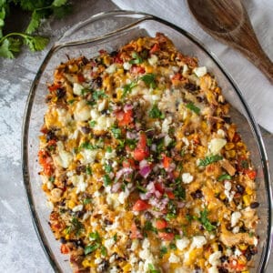 Leftover turkey southwestern casserole in clear baking dish on light background.