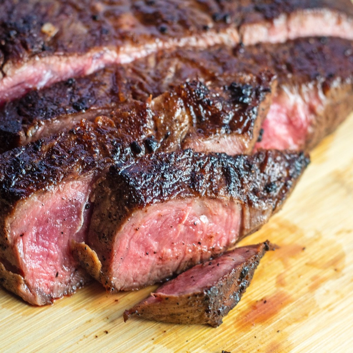 Closeup pada panci irisan steak besi datar di atas talenan.