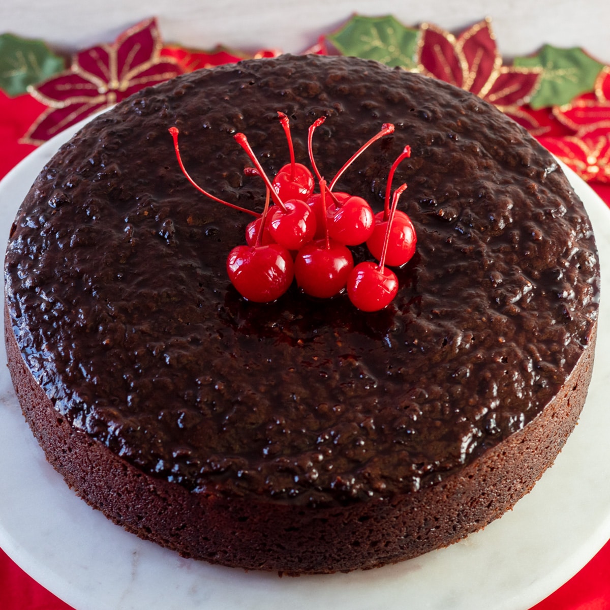 Imagem quadrada olhando para o bolo preto jamaicano, com cerejas em cima do bolo.