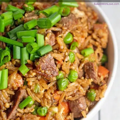 Pin image with text of prime rib fried rice in a white bowl with green onion on top.