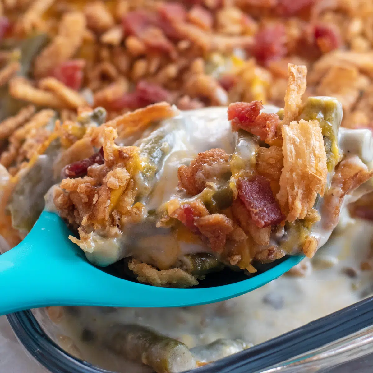 Bacon cheddar green bean casserole being spooned out of dish.