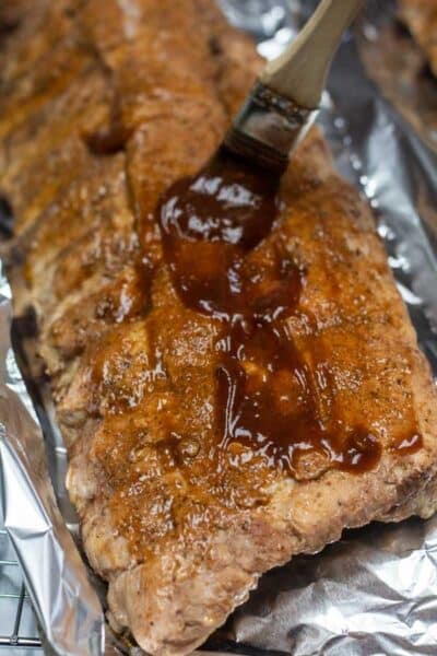 Process photo showing applying bbq sauce to ribs.