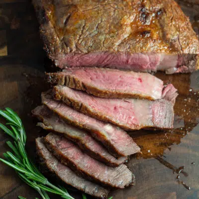 A broiled ribeye steak on a wood cutting board sliced.