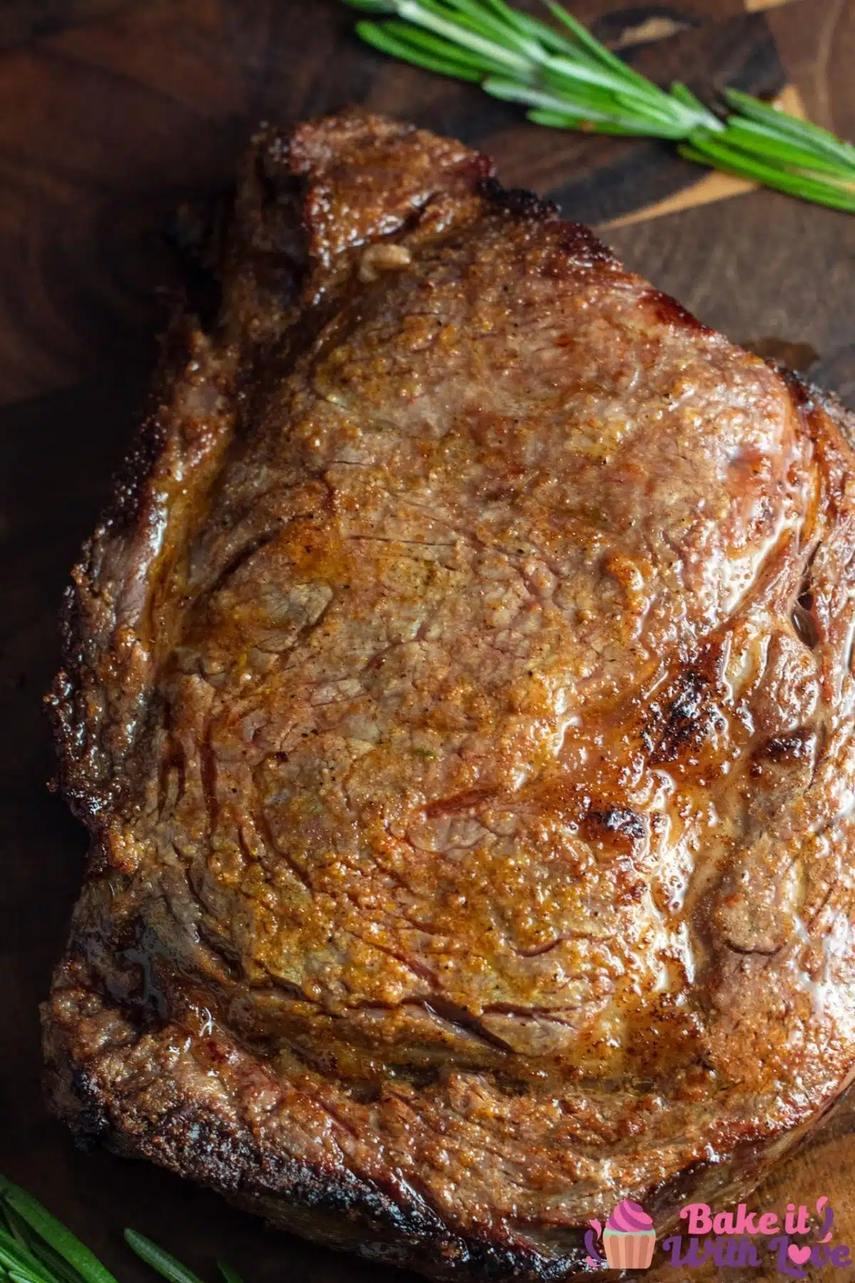 A tall image of broiled ribeye steak on a wood cutting board.