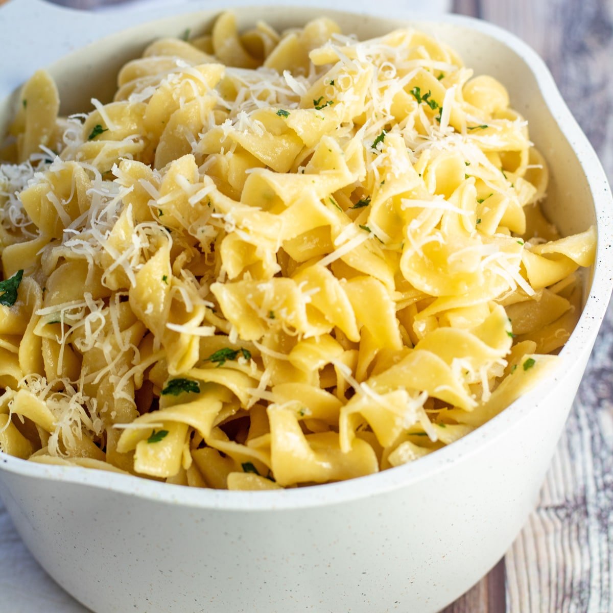 Fideos fáciles untados con mantequilla en una cacerola blanca con parmesano.