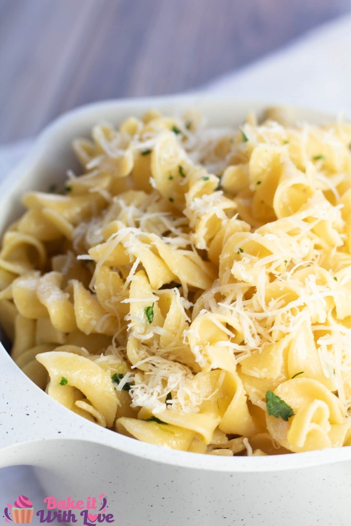 Tall image of buttered noodles in white saucepan.