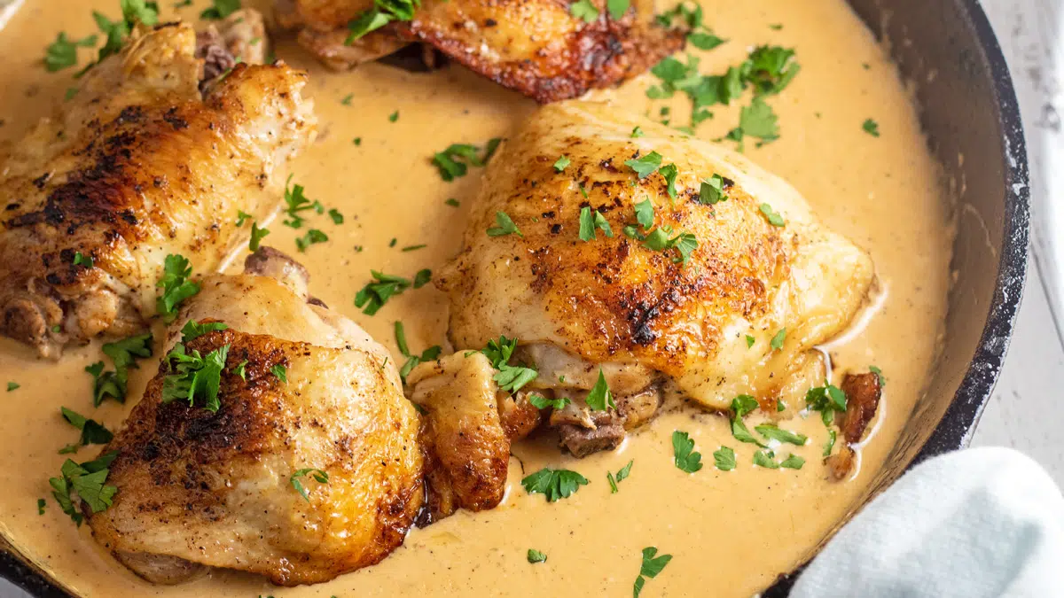 Wide image of cream cheese chicken in a cast iron pan.