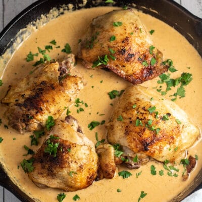 Square image of cream cheese chicken in a cast iron pan.