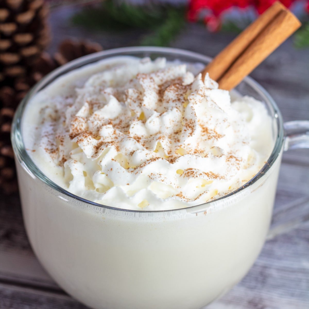 Classic eggnog served in clear mug with whipped cream.