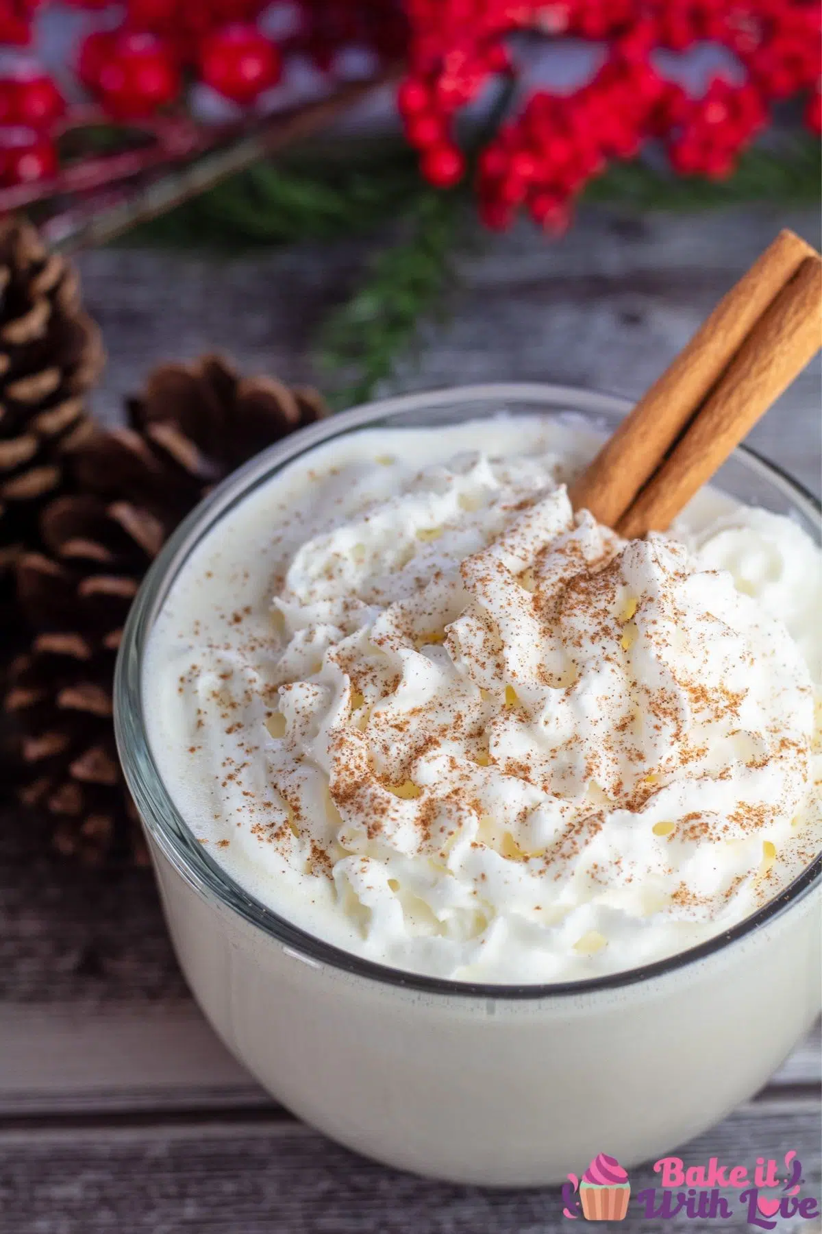 Tasty homemade eggnog in mug with pinecones and holly decor.
