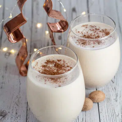 Square photo of two glasses of gingerbread eggnog on a white background.