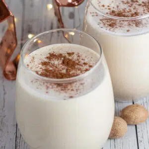 Close up square photo of two glasses of gingerbread eggnog on a white background.