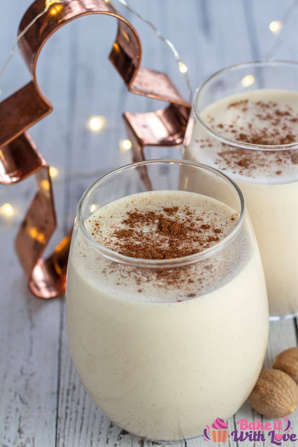 Tall photo of two glasses of gingerbread eggnog on a white background.