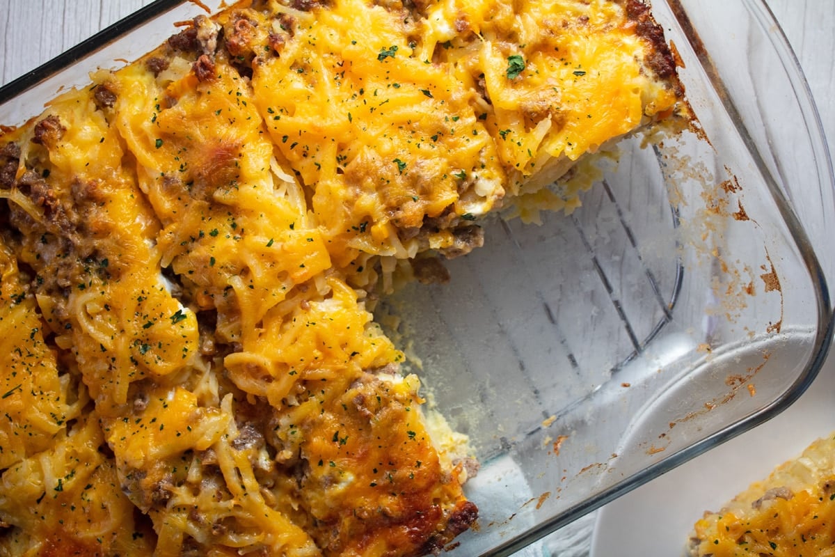 Wide image of the sausage hash brown breakfast casserole in baking dish with slices removed.