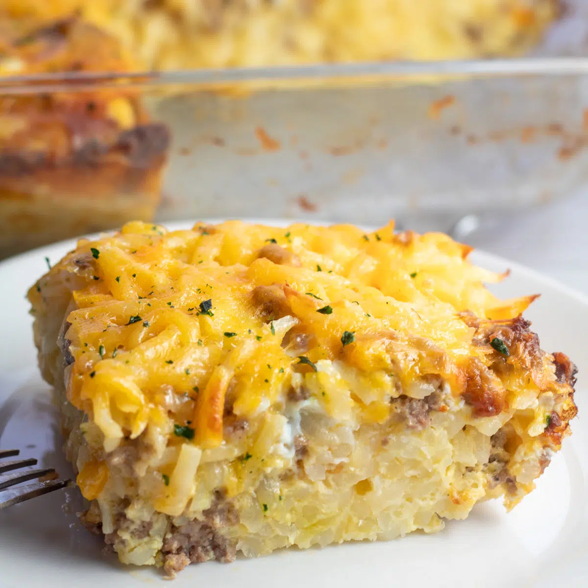 Caçarola de café da manhã com salsicha hash brown fatiada e servida no prato branco.