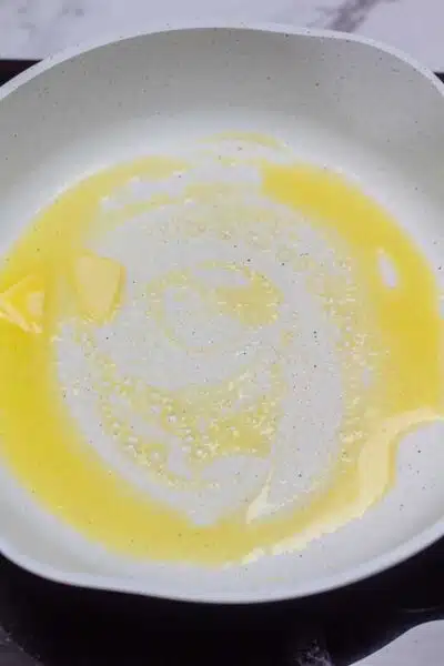 Process photo showing butter melted in frying pan.