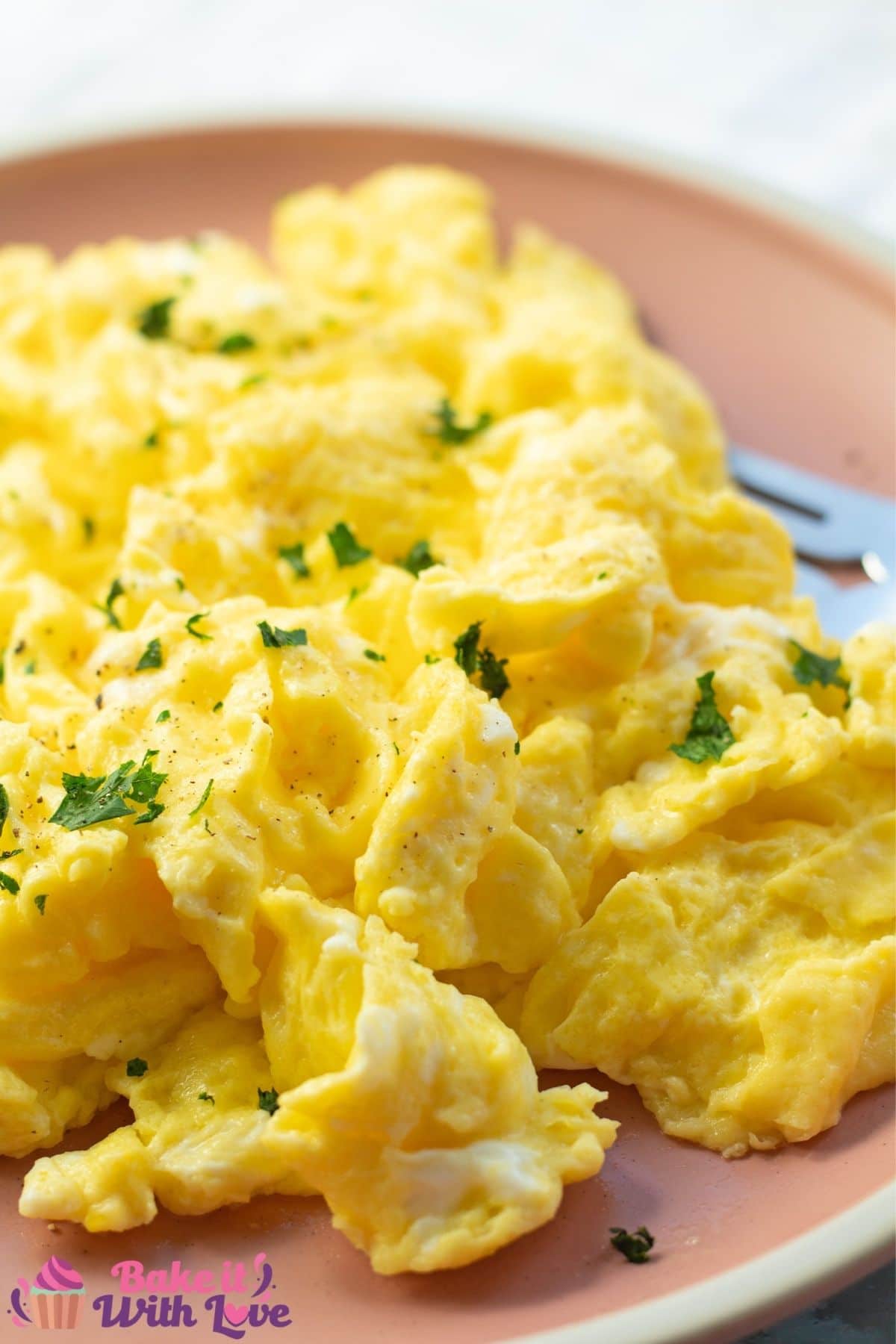 Tall image of scrambled eggs on a pink plate.