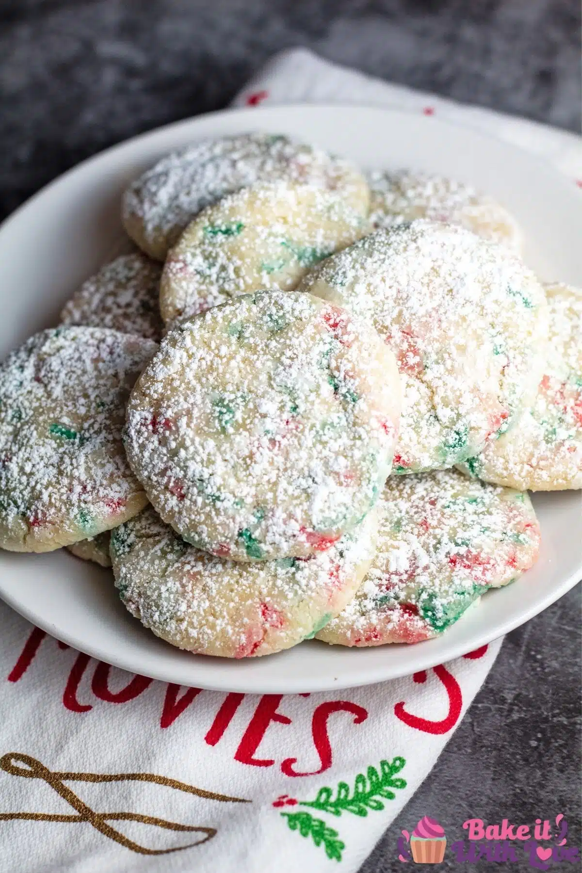Tall image of sprinkle Christmas cookies on a white plate with a grey background.