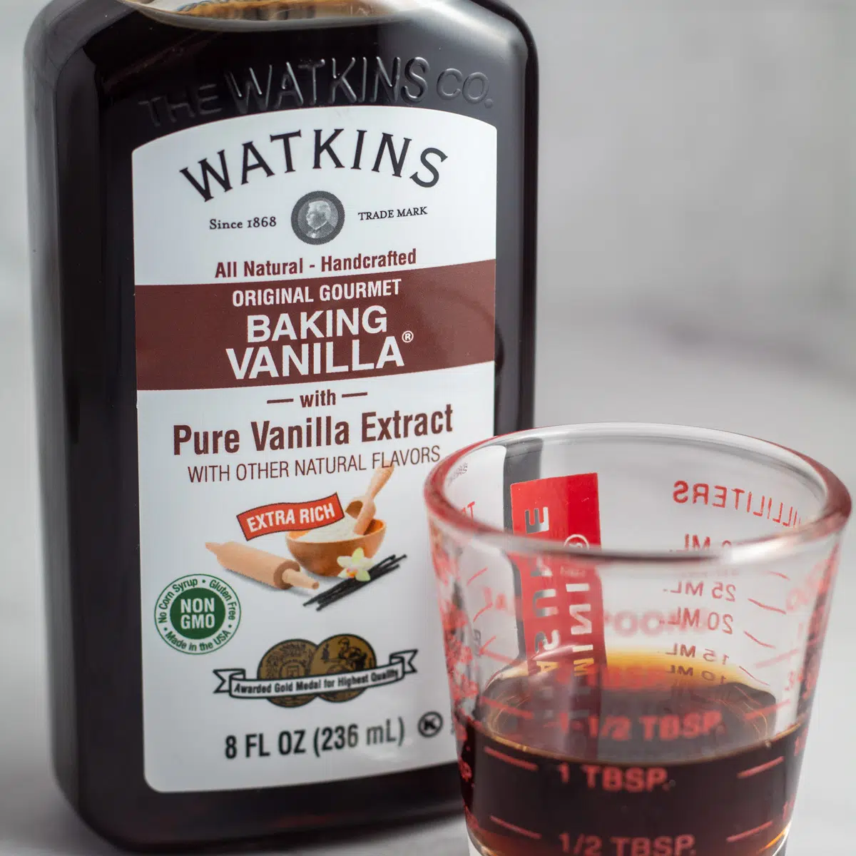 Vanilla extract substitute options with bottled vanilla and a portion in measuring cup.