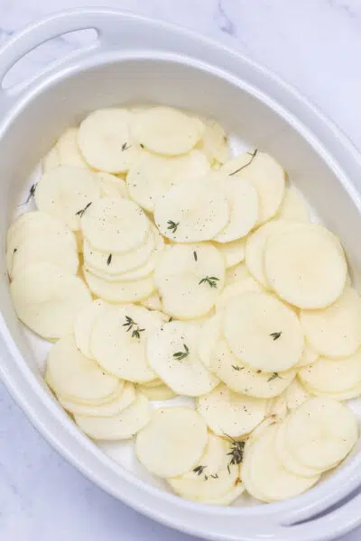 Process photo 2 layer the sliced potatoes into your prepared baking dish, then season.