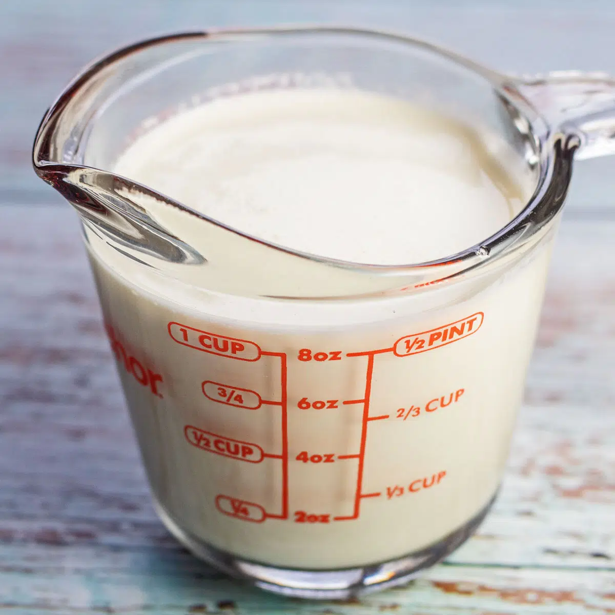 Crema espesa vs crema batida espesa imagen de crema batida espesa en una taza medidora.