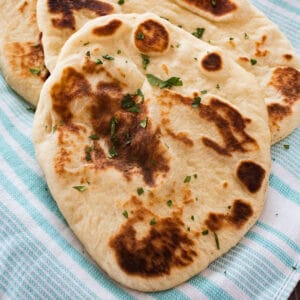 Square image of naan bread on a blue towel.