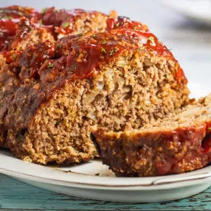 Square image of the sliced meatloaf with oatmeal on white platter.