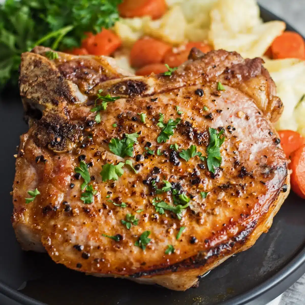 Pork chop on a black plate.