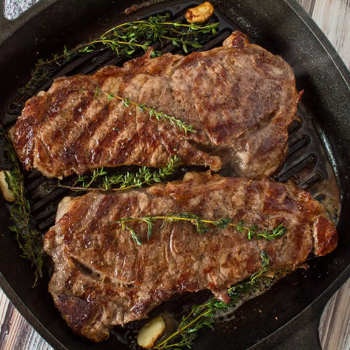 Image carrée au-dessus de 2 steaks dans une poêle en fonte.