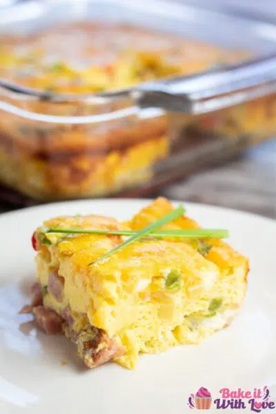 Tall image of the baked Denver omelet on white plate with fresh chives.