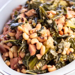 Southern black eyed peas with collard greens and ham in serving bowl.