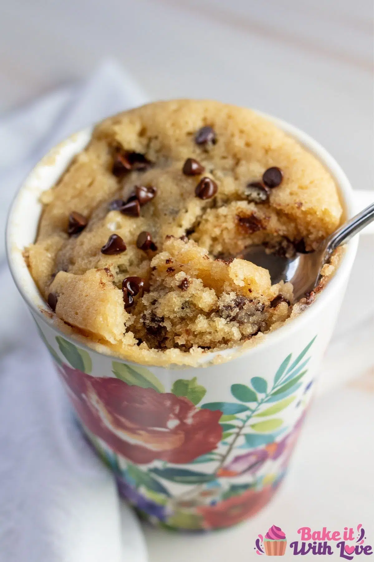 Tall image of flowered mug with chocolate chip cake.