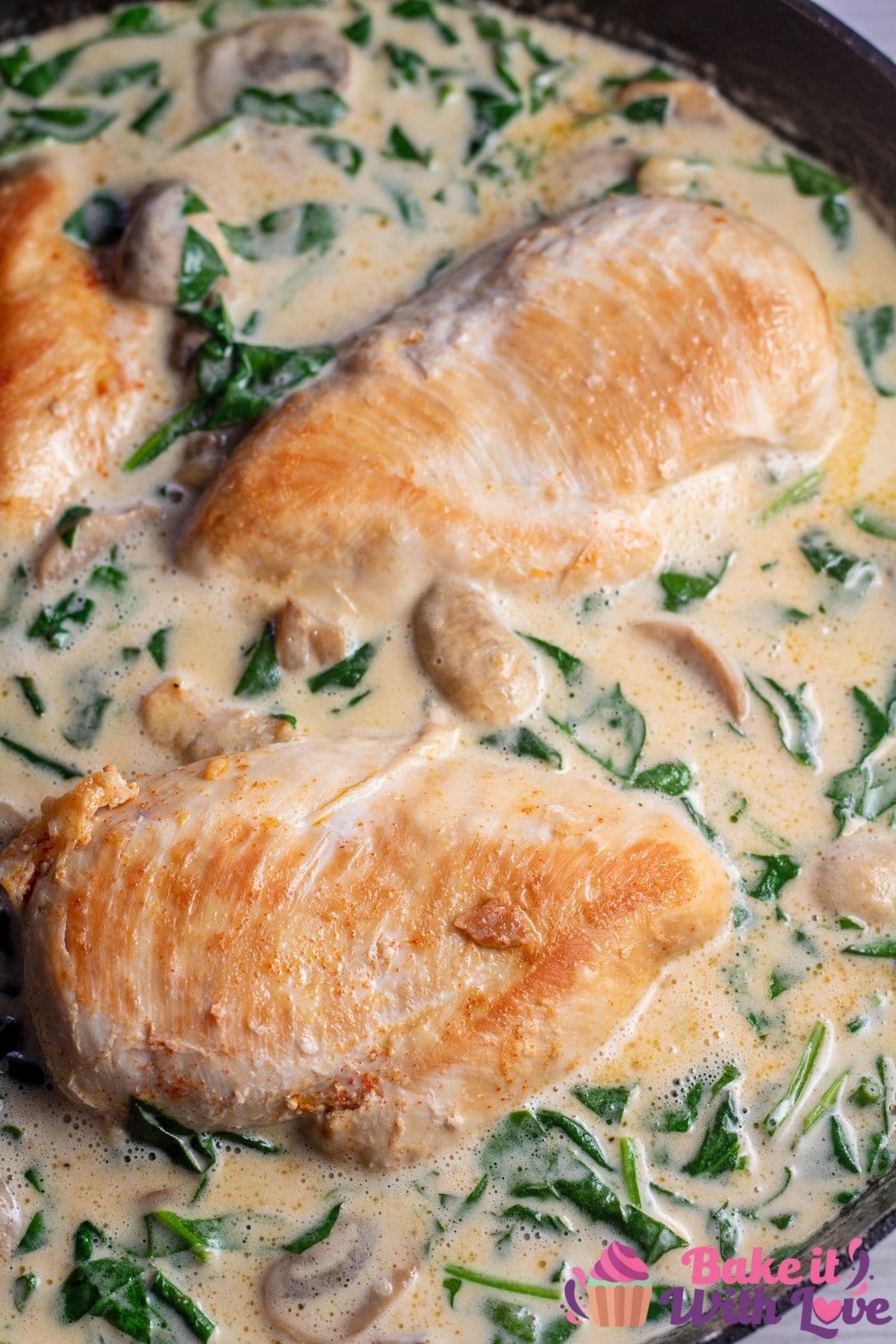 Tall image of chicken in creamy Parmesan sauce in a skillet.