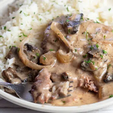 Wide image of crockpot cube steak served with rice.