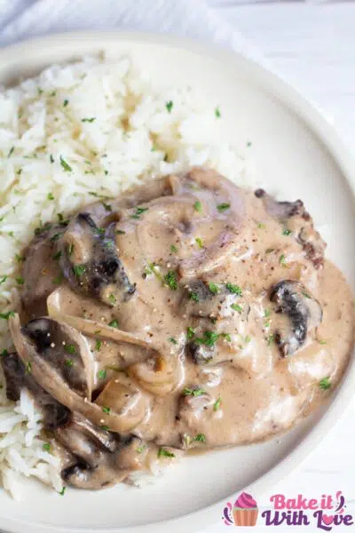 Tall image of crockpot cube steak served with rice.
