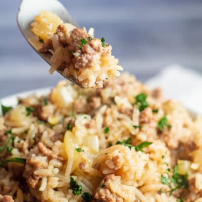 Square image of dirty rice with fork taking a bite.