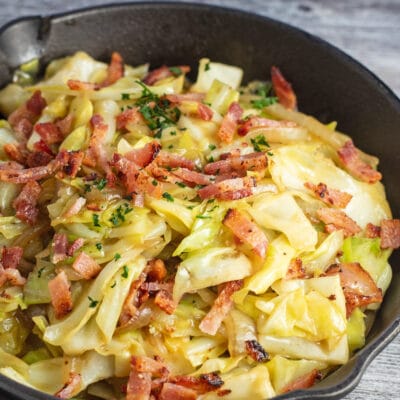Square image of a cast iron pan with Southern fried cabbage with bacon.
