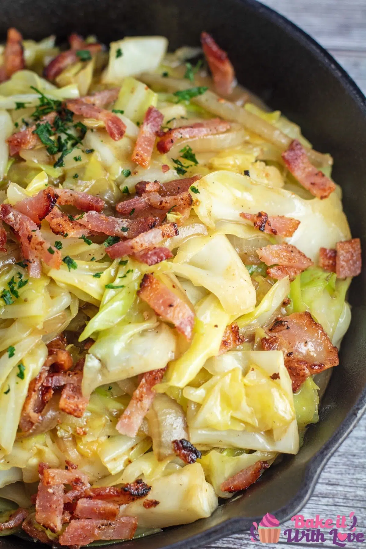 Tall Image of a cast iron pan with Southern fried cabbage with bacon.