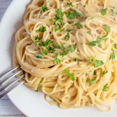Square photo of garlic Parmesan angel hair pasta on white plate.