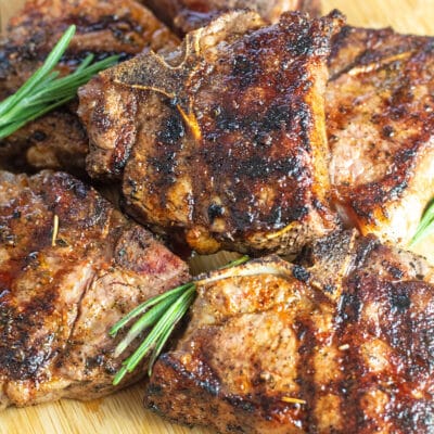 Square image of grilled lamb chops on a wooden cutting board.