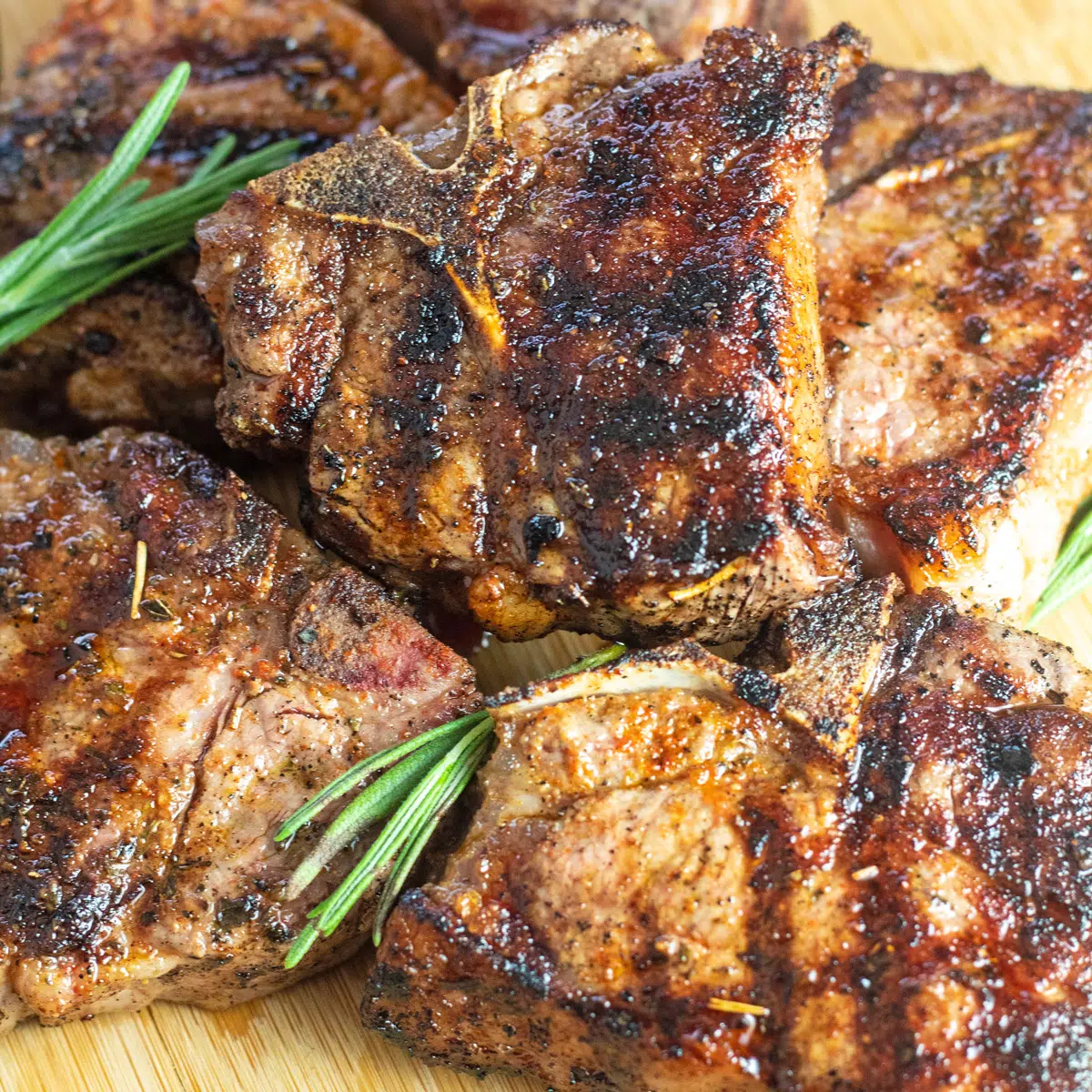 Square image of grilled lamb chops on a wooden cutting board.