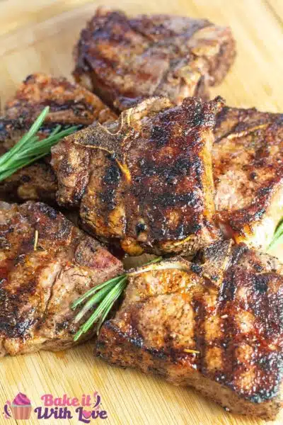 Tall image of grilled lamb chops on a wooden cutting board.